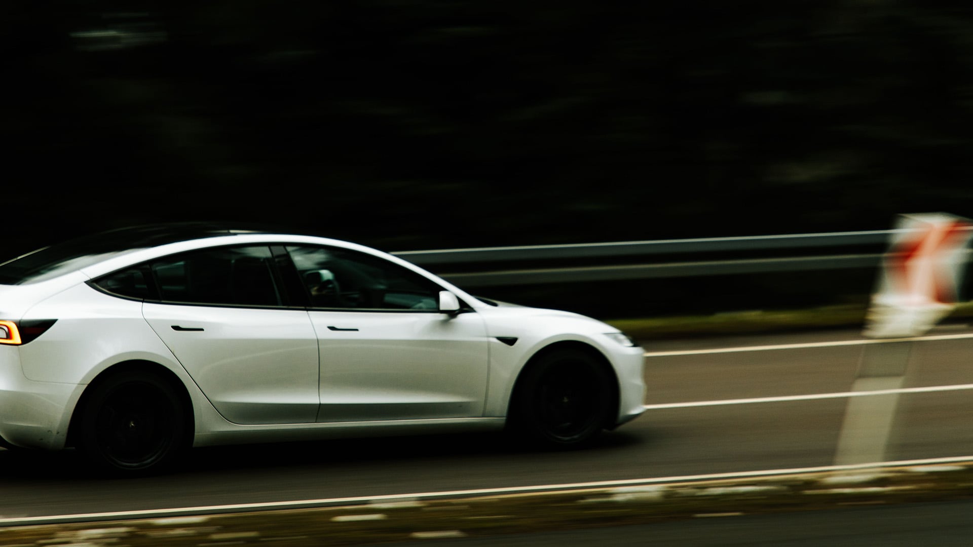 Vit Tesla Model 3 kör på landsväg.