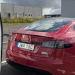 Röd Tesla Model S laddar vid en Tesla Supercharger.
