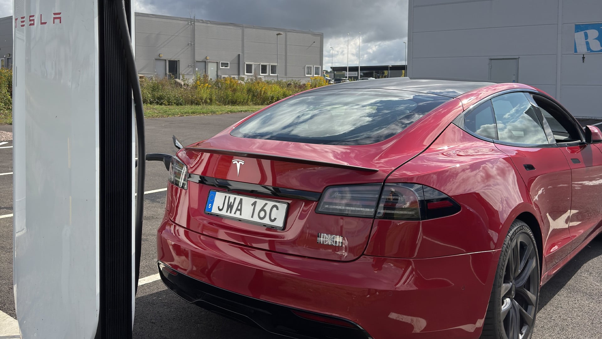 Röd Tesla Model S laddar vid en Tesla Supercharger.