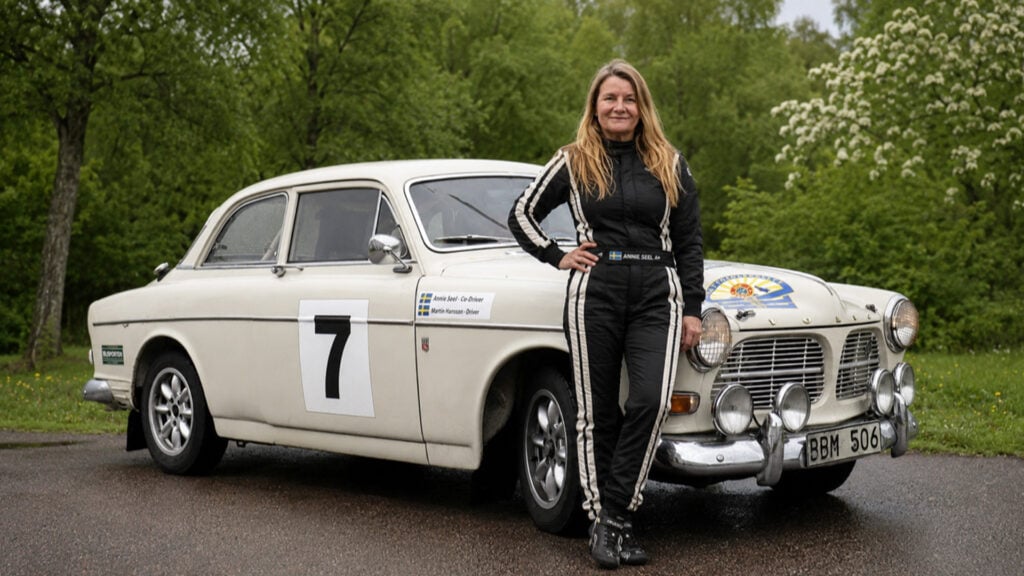 Annie Seel står framför en vit Volvo Amazon.