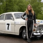 Annie Seel står framför en vit Volvo Amazon.