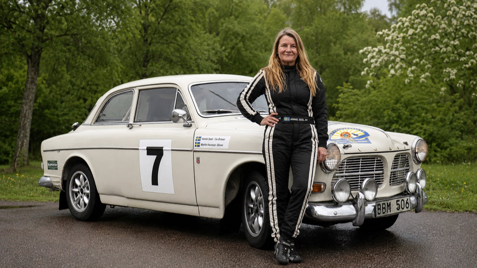 Annie Seel står framför en vit Volvo Amazon.
