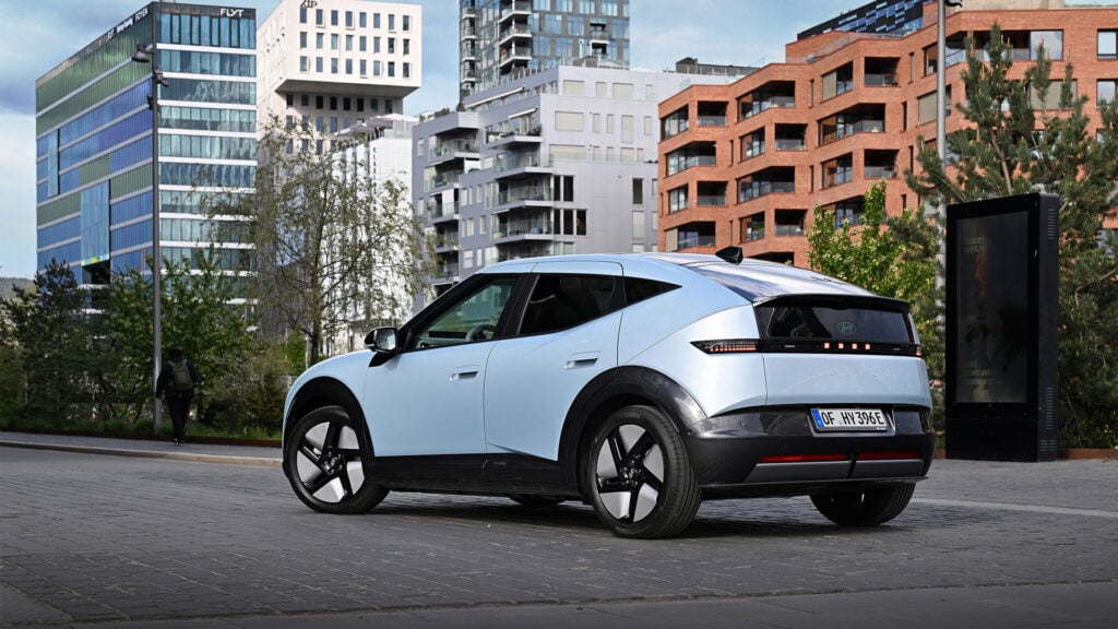 Blå Hyundai Ioniq 3 snett bakifrån på en parkering i urban miljö.