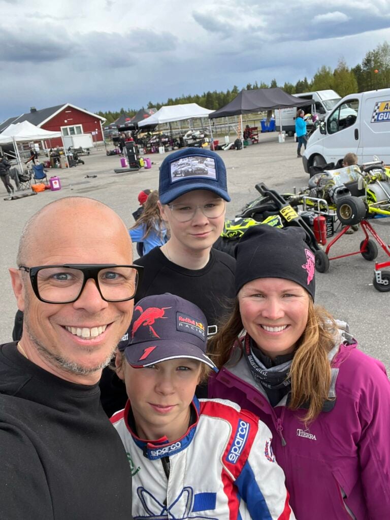 Hela familjen Olert leendes mot kameran på en gokart-tävling.