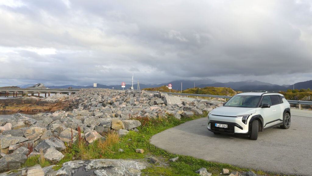 Ljusgrå Kia EV3 GT parkerad med fina norska berg i bakgrunden. 