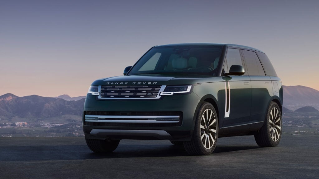 Grön Range Rover Electric snett framifrån med fin utsikt i bakgrunden.