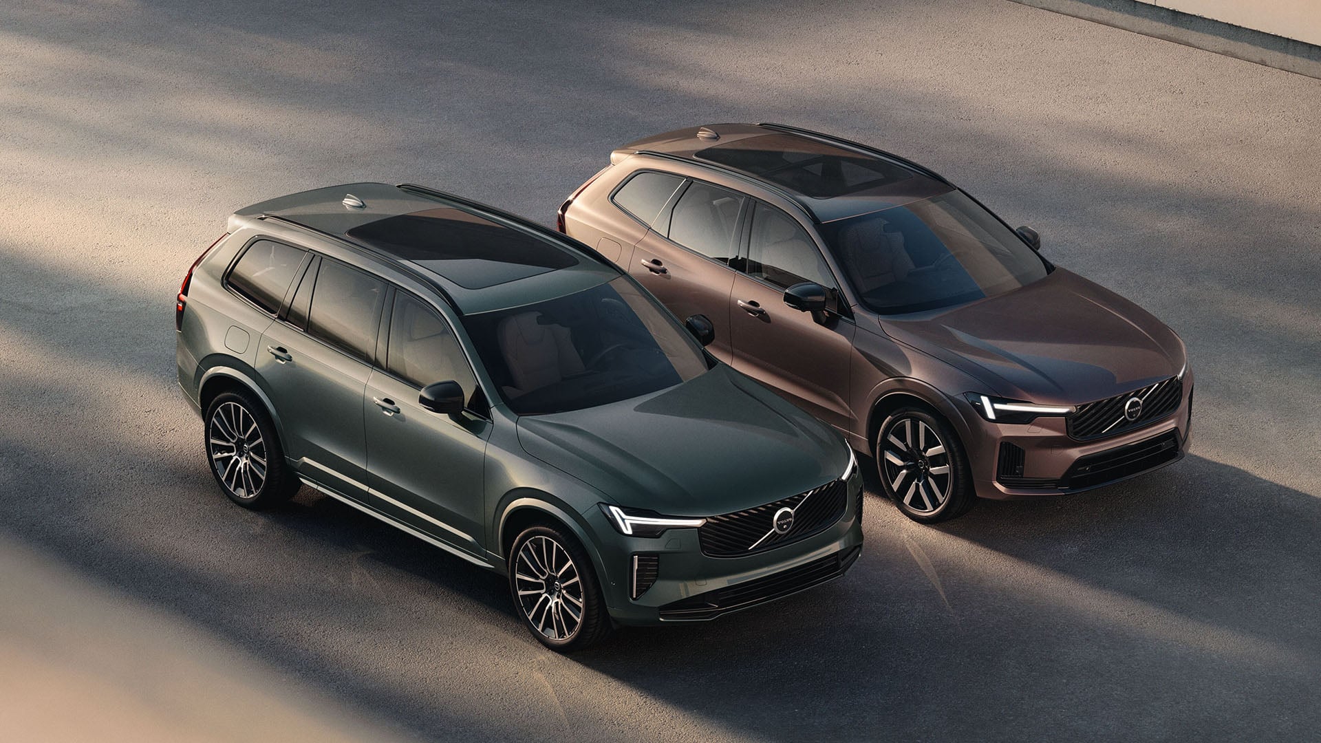 Grön Volvo XC90 bredvid en copparfärgad Volvo XC60.