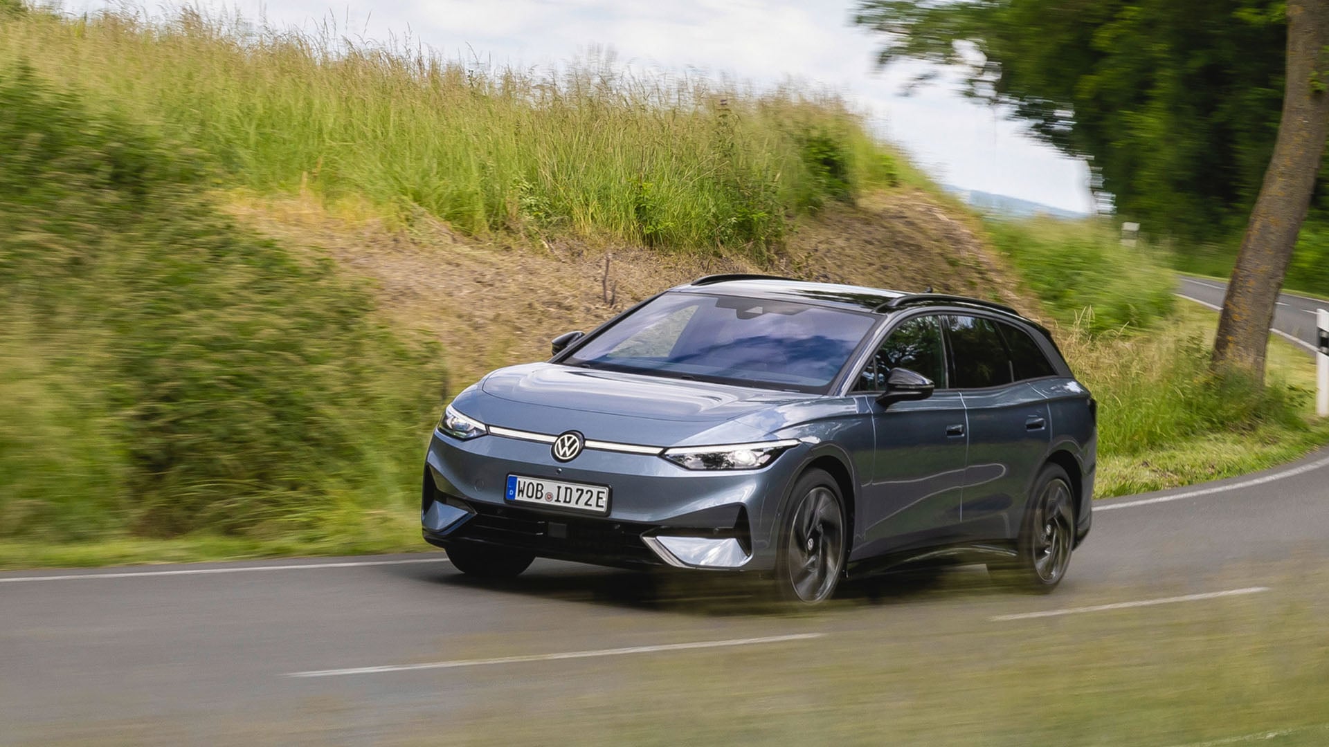 En silvergrå VW ID. 7 Tourer kör på en landsväg.