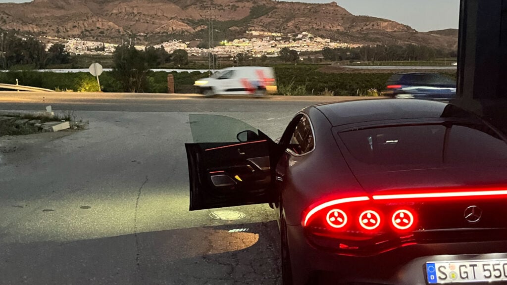 Svart Mercedes-AMG GT 4-Door bakifrån med berg och väg i bakgrunden.
