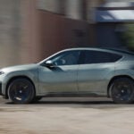 Grå BMW iX4 Neue Klasse i profil i dynamisk vy.