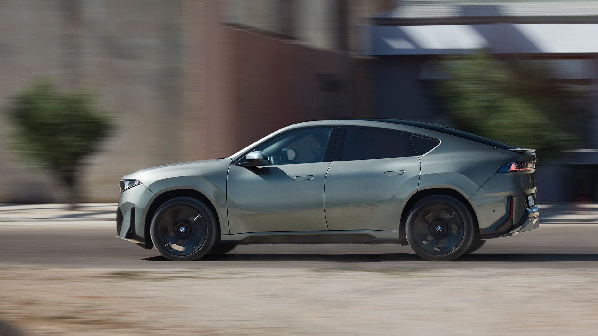 Grå BMW iX4 Neue Klasse i profil i dynamisk vy.