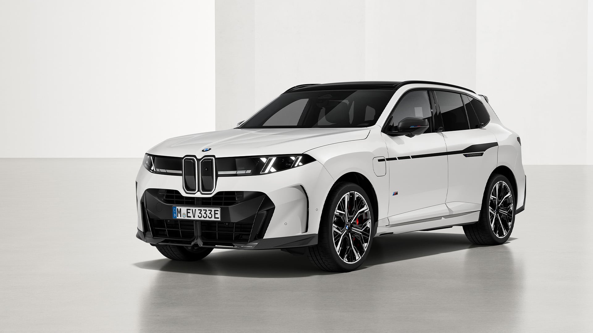 Vit BMW X5 snett framifrån i studio.