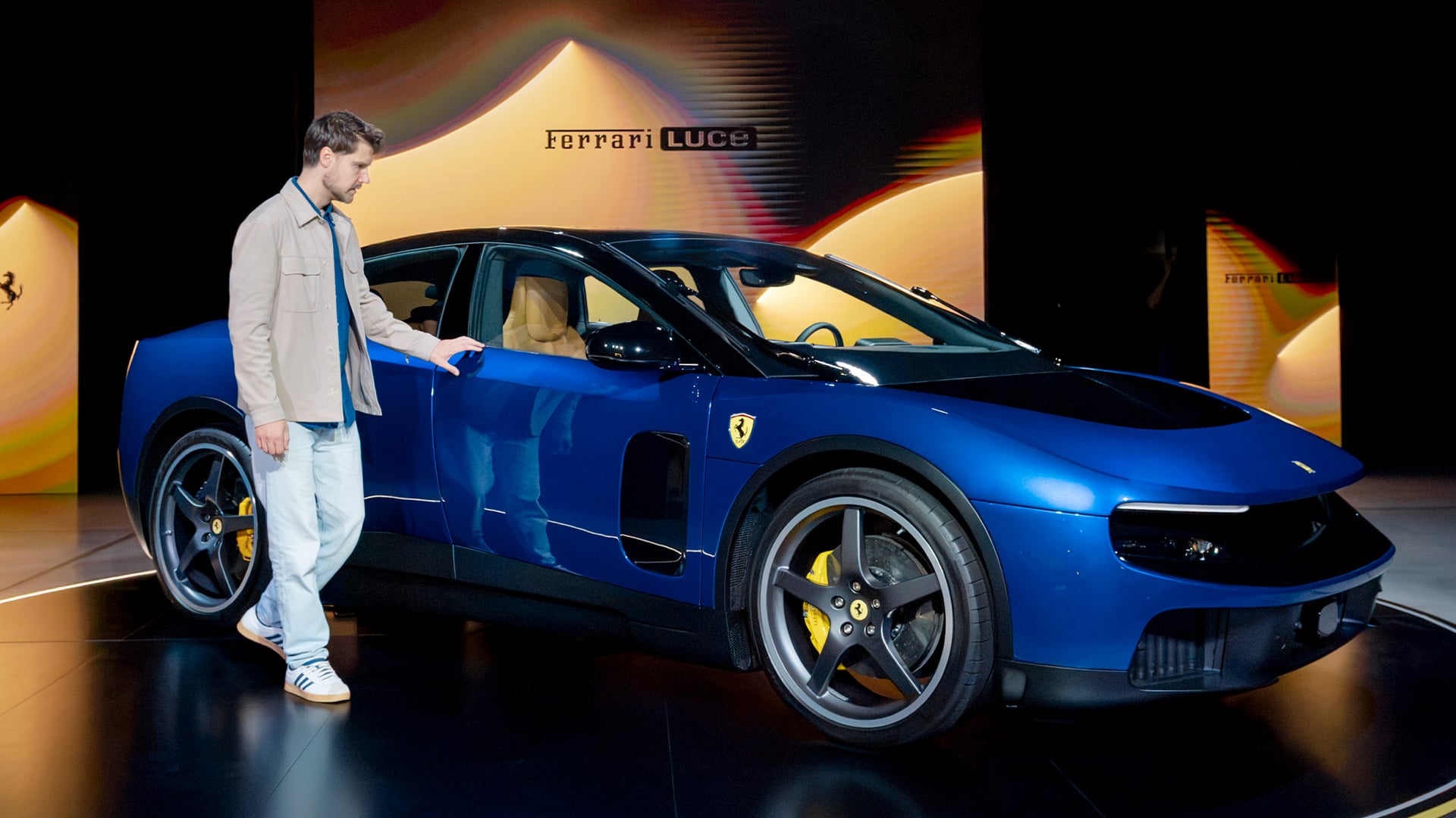 John Sempill står vid passagerarsidan till en blå Ferrari Luce.