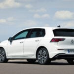 Vit Volkswagen Golf snett bakifrån på öppen mark.