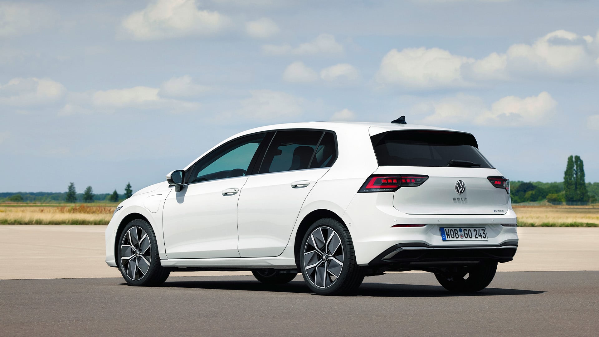Vit Volkswagen Golf snett bakifrån på öppen mark.