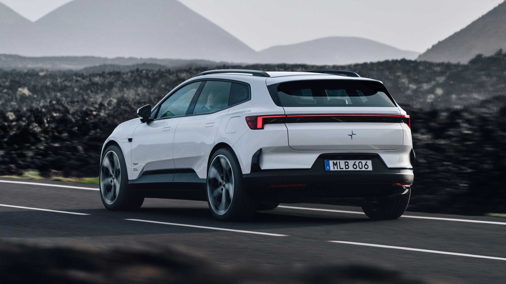 Vit Polestar 4 fotograferad bakifrån under körning på väg i bergslandskap.